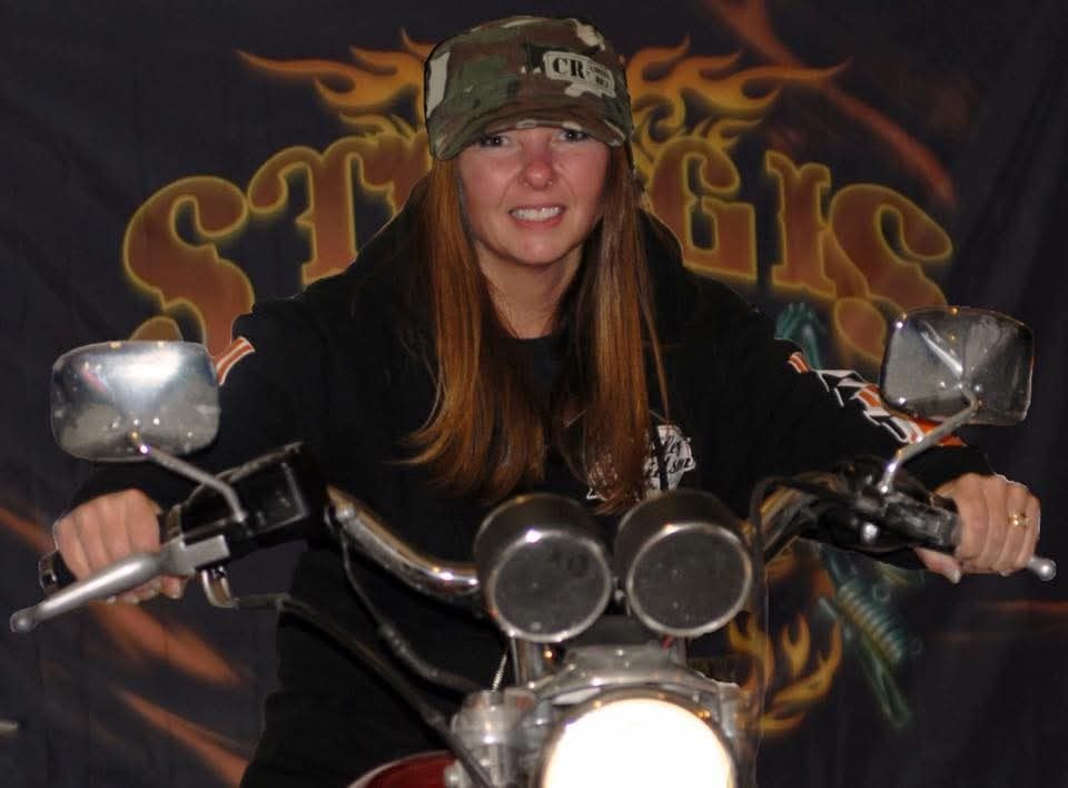 Dawn on a motorcycle in front of a Sturgis banner