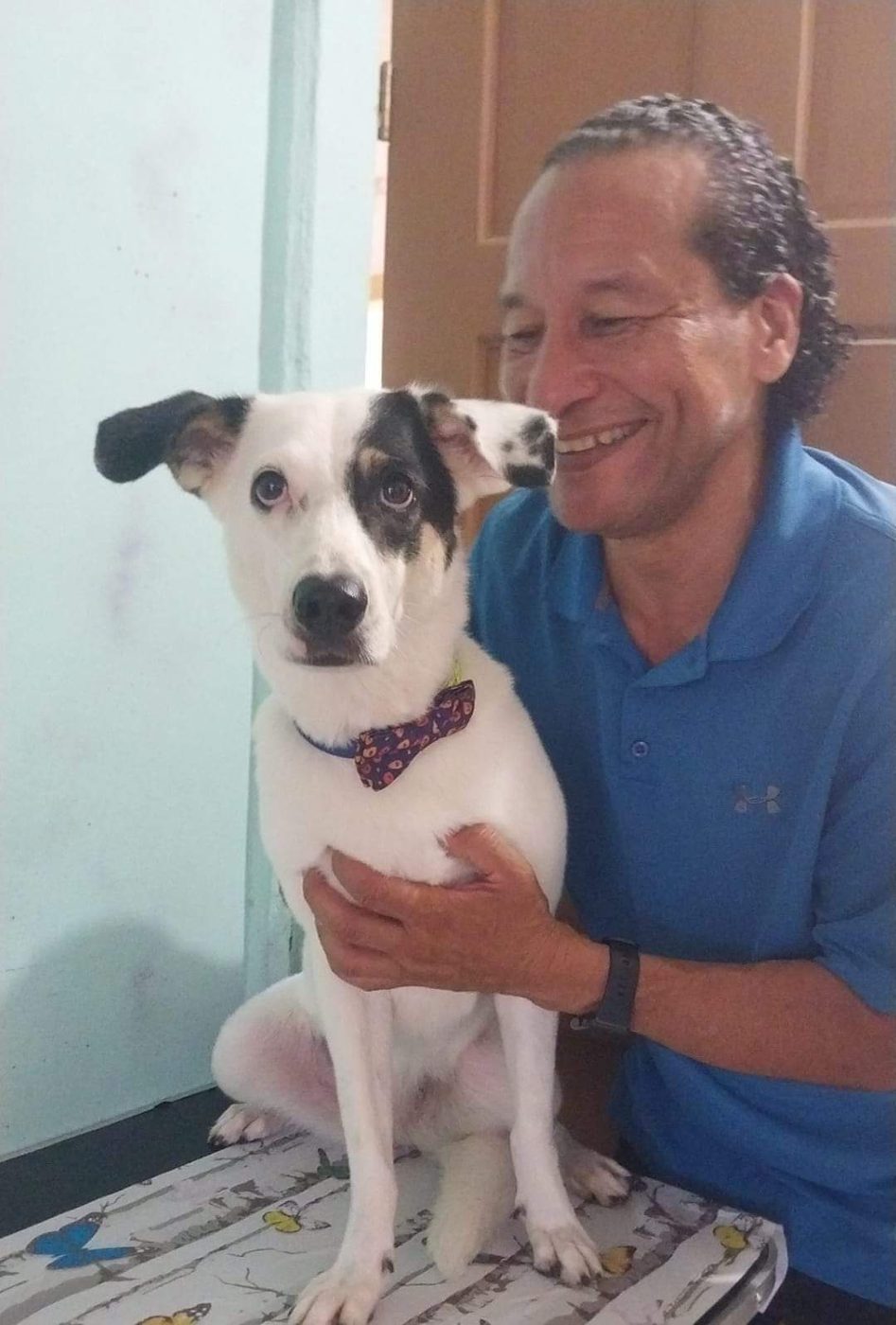 Nolberto with a white and black rescue dog wearing a bow tie